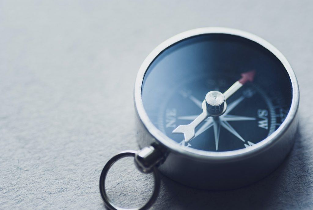 Small magnetic compass on a grey background